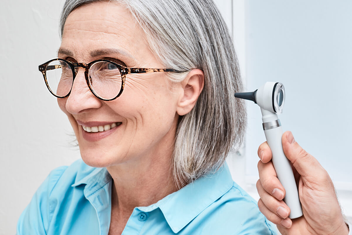 Otolaryngologist examining patient ear with otoscope