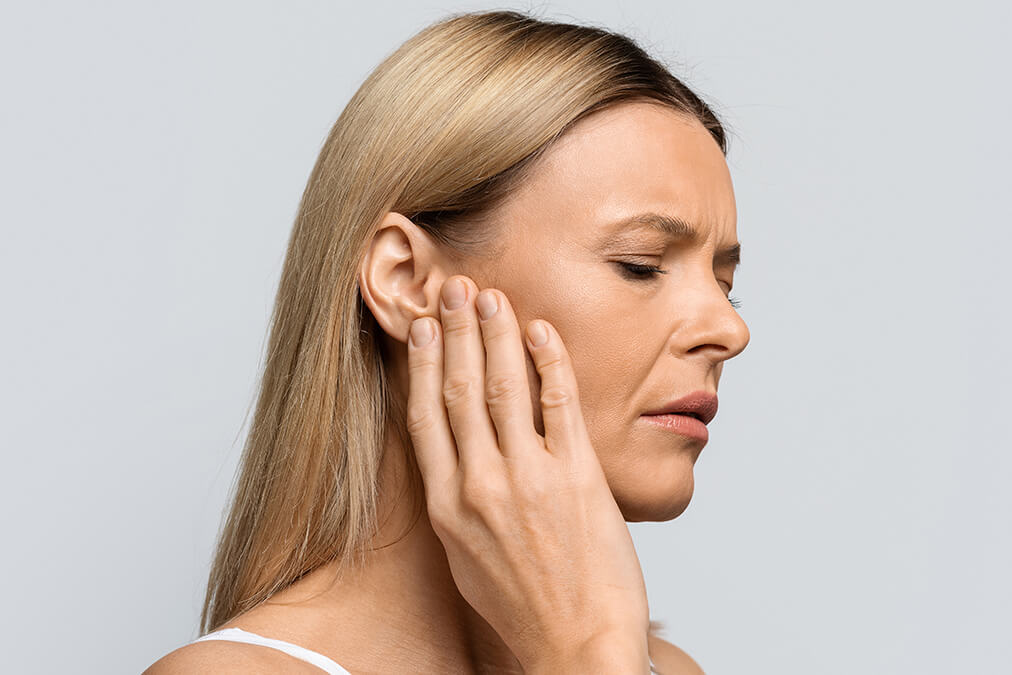 Middle aged woman holding hand up to ear in pain